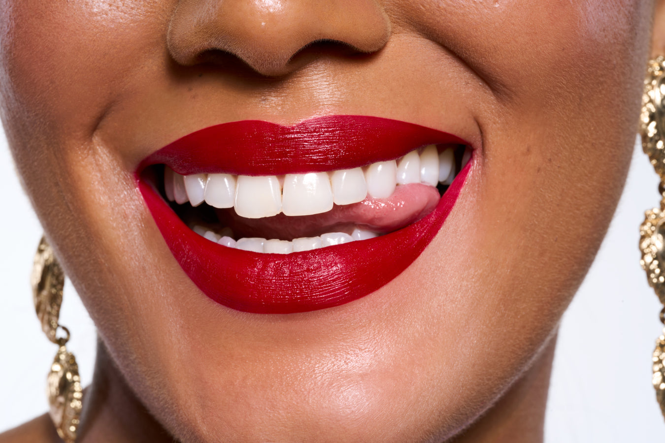 Close-up of a person's face with red lipstick and gold earrings.