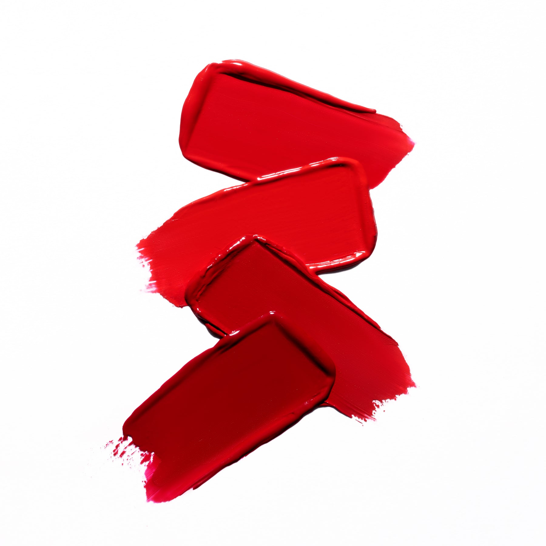 Three swatches of red lipstick on a white background